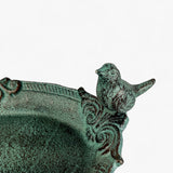Close-up of cast iron bird bath rim with ornate scrollwork design and green patina finish bird sculpture