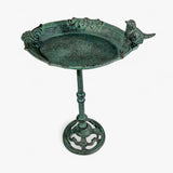 Cast iron bird bath close-up showing decorative bowl edges, green patina, and ceramic bird sculpture