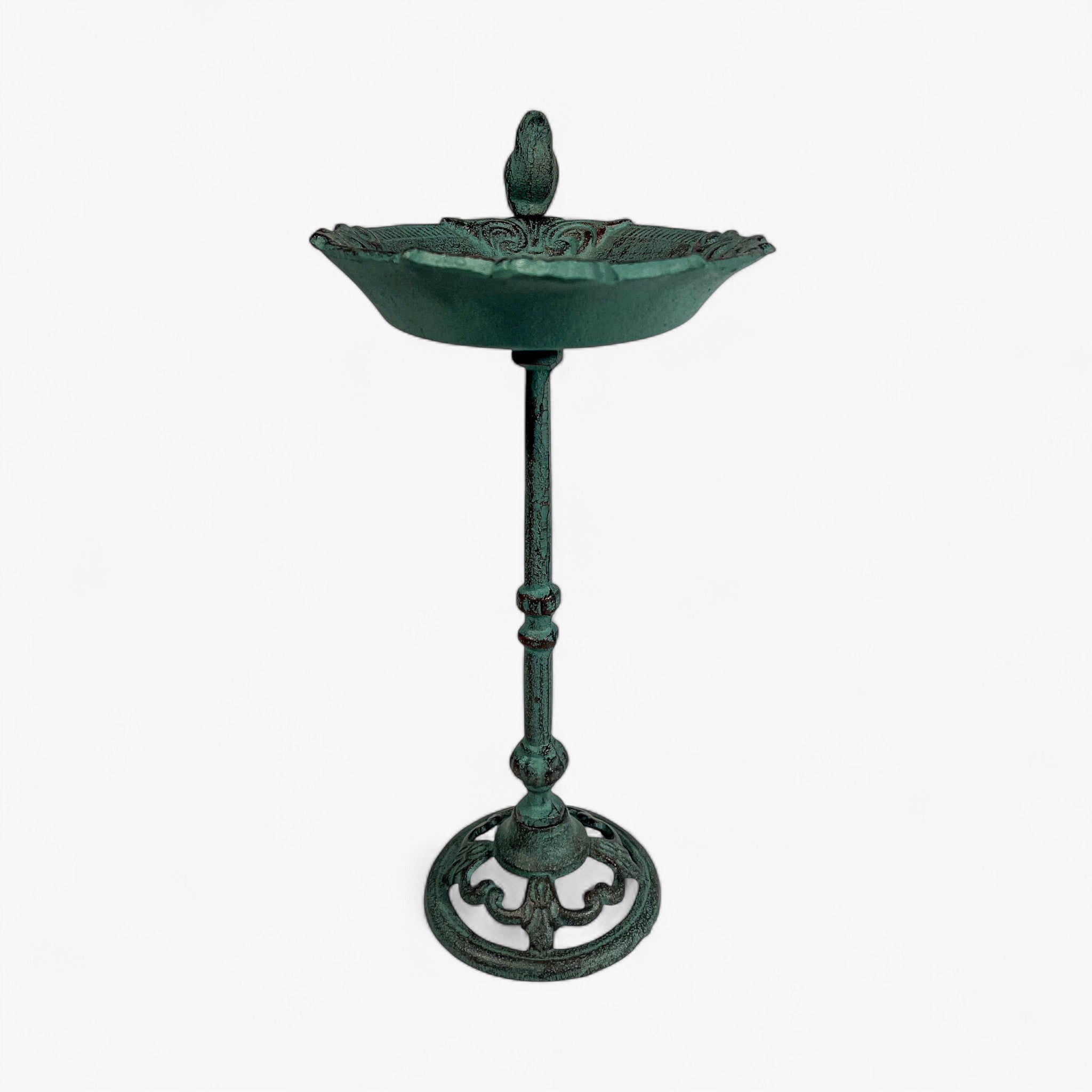 Front-facing cast iron pedestal bird bath in green verdigris patina with symmetrical design and bird