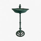 Front-facing cast iron pedestal bird bath in green verdigris patina with symmetrical design and bird