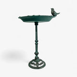 Side profile of green patina cast iron bird bath with perched bird and turned pedestal stem detail