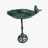 Overhead angled view of ornate cast iron bird bath showing bowl shape, patina weathering, and bird accent
