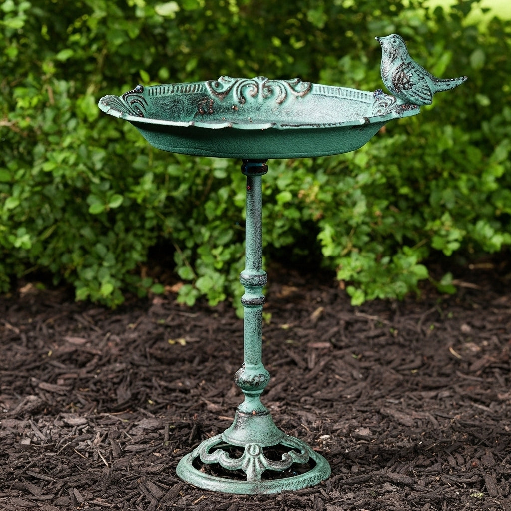 Green patina cast iron pedestal bird bath with ornate bowl, perched bird, and decorative base in garden