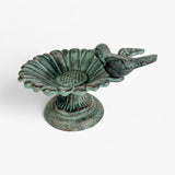 Cast iron verdigris bird bath with scalloped sunflower design and bird, side angle