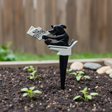 Black cast iron dog garden stake with No Pooping sign in garden bed setting