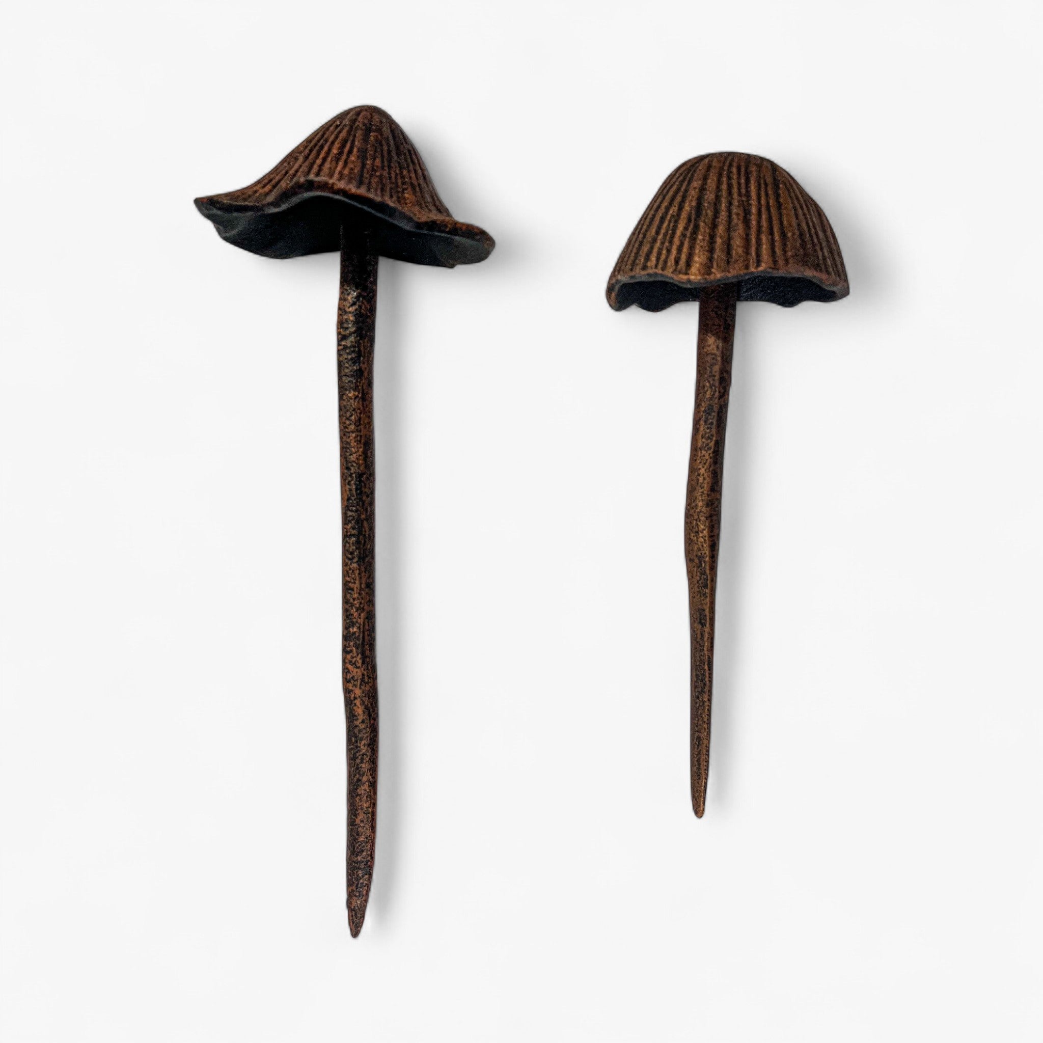 Pair of copper-finish mushroom garden stakes with fluted caps and aged patina detail