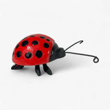 Red and black cast iron ladybug sculpture with articulated antennae side view