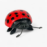 Red and black cast iron ladybug with tripod leg stance and curved antennae