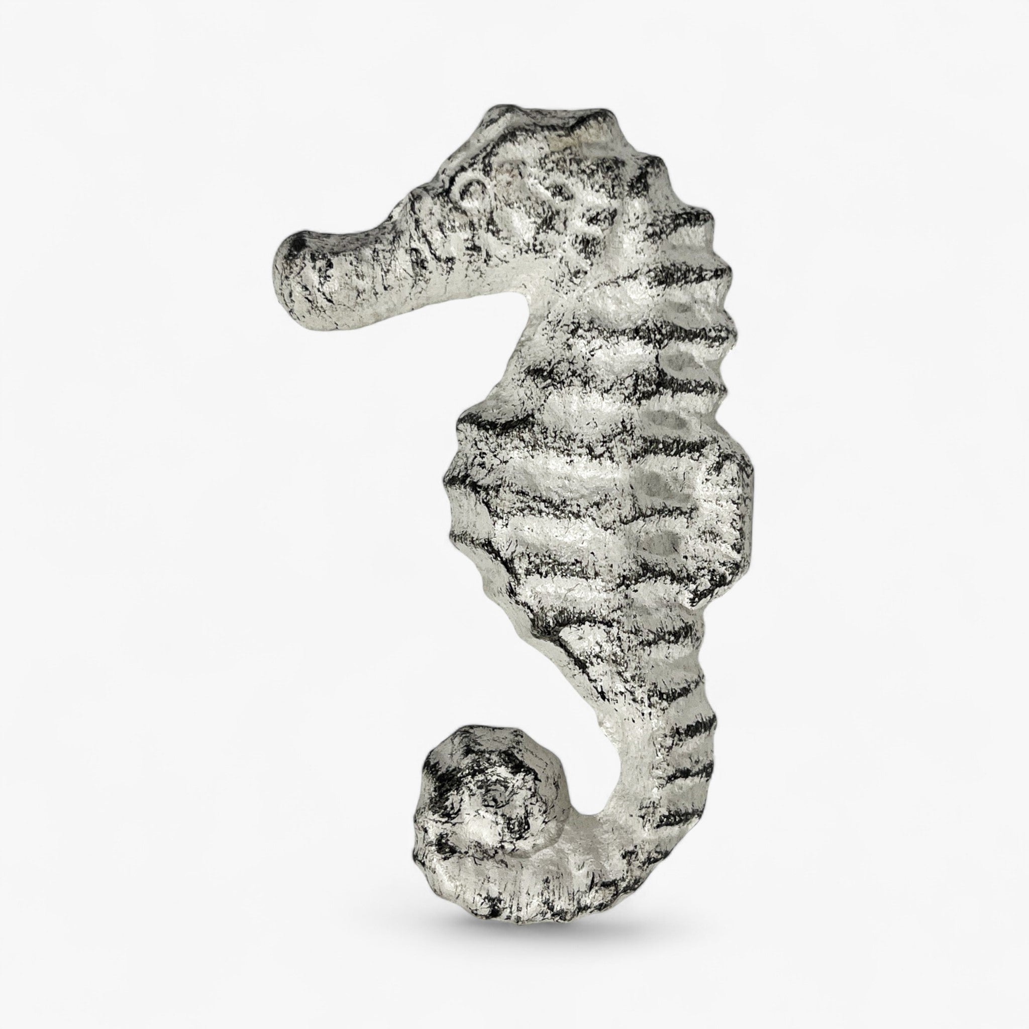 White cast iron seahorse knob showing side profile with aged patina and ribbed details