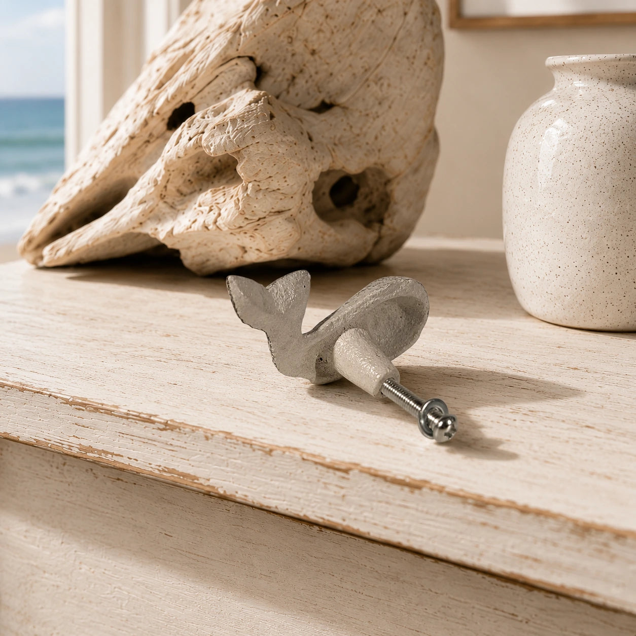 Back view of white whale drawer knob with mounting screw on a distressed tabletop