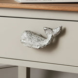 Weathered white cast iron whale drawer knob with textured finish on cream cabinet