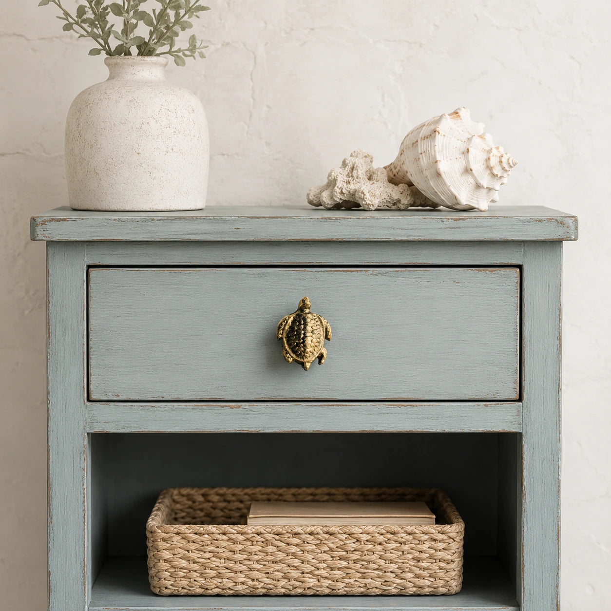 Coastal nightstand with brass sea turtle drawer knob, basket, and shell decor
