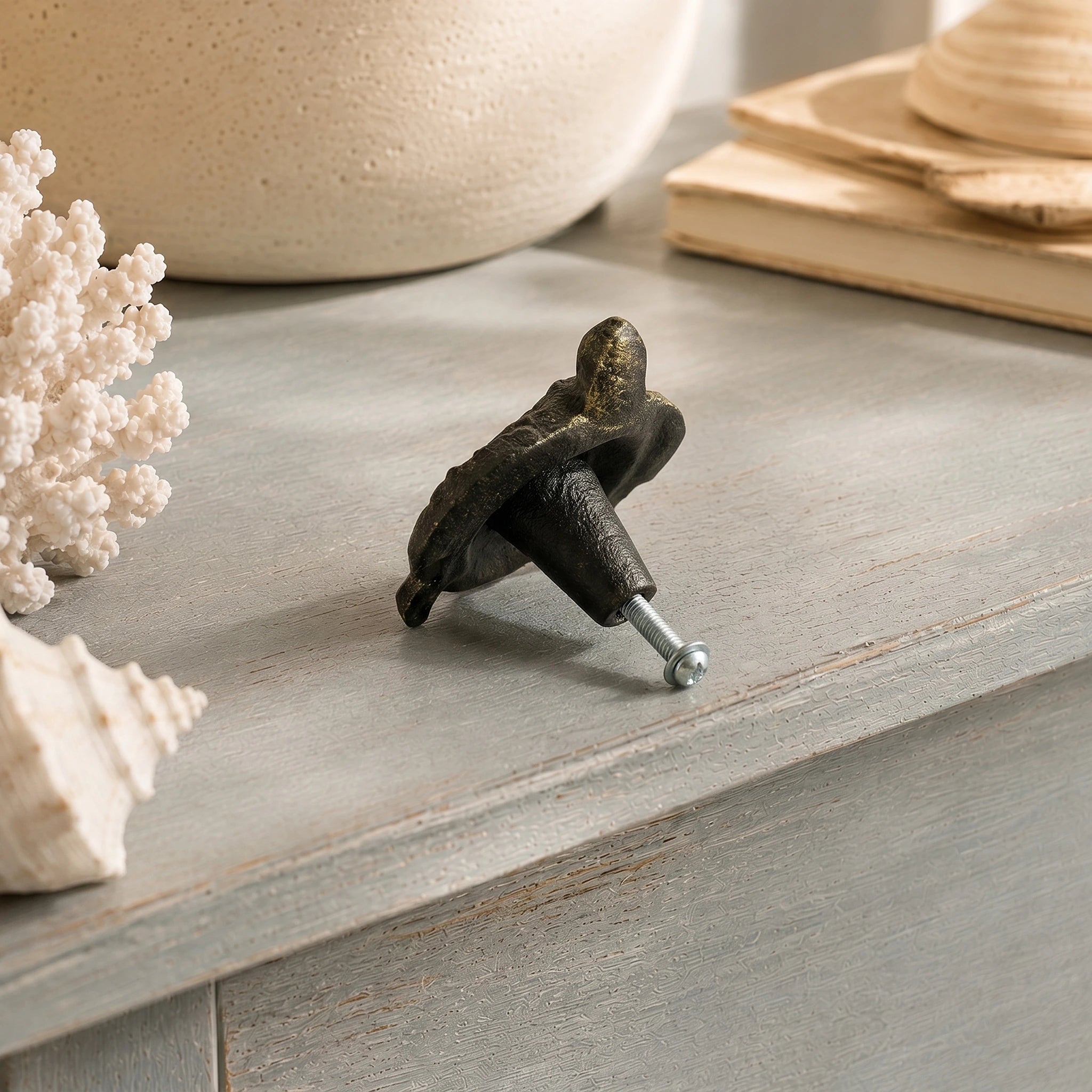 Back view of sea turtle drawer knob with mounting screw on distressed blue wood surface