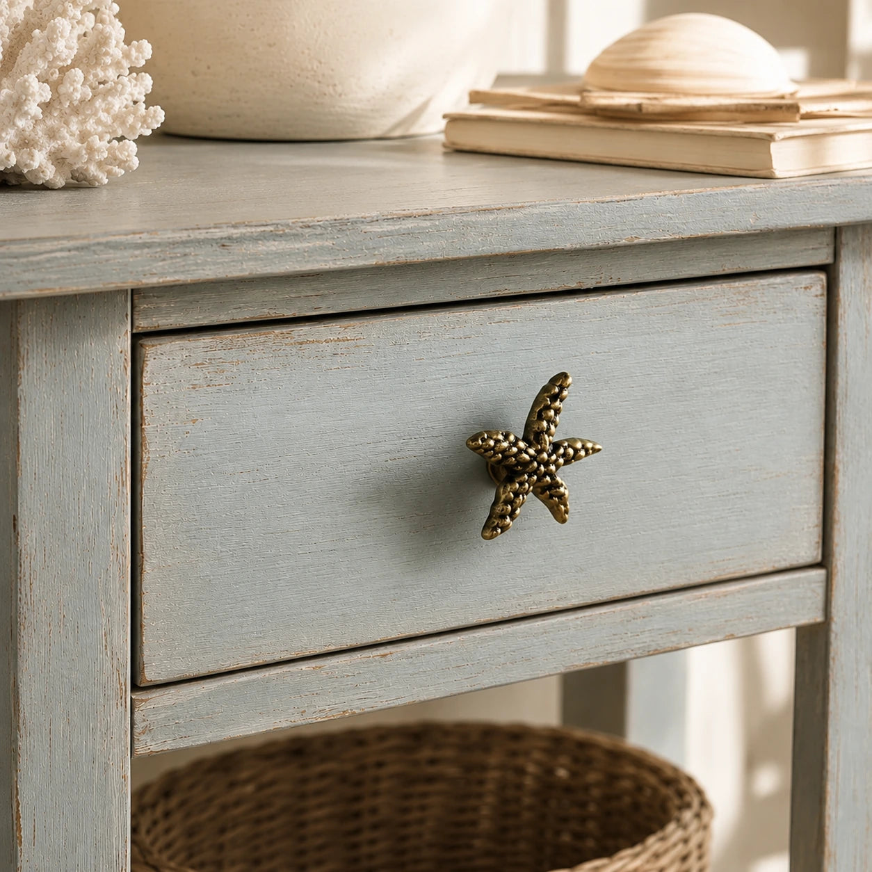 Angled close-up of brass starfish cabinet knob on a weathered blue drawer front