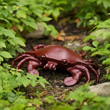 Red cast iron crab key holder on moss ground among ferns, outdoor coastal decor