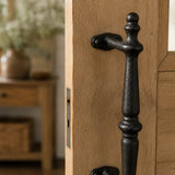 Close-up of black cast iron door pull handle with mounting plate and screw