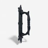 Black cast iron door pull hardware with decorative baroque details and curved grip
