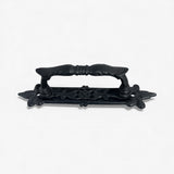 Ornate black cast iron door handle with floral base plate and vintage grip design