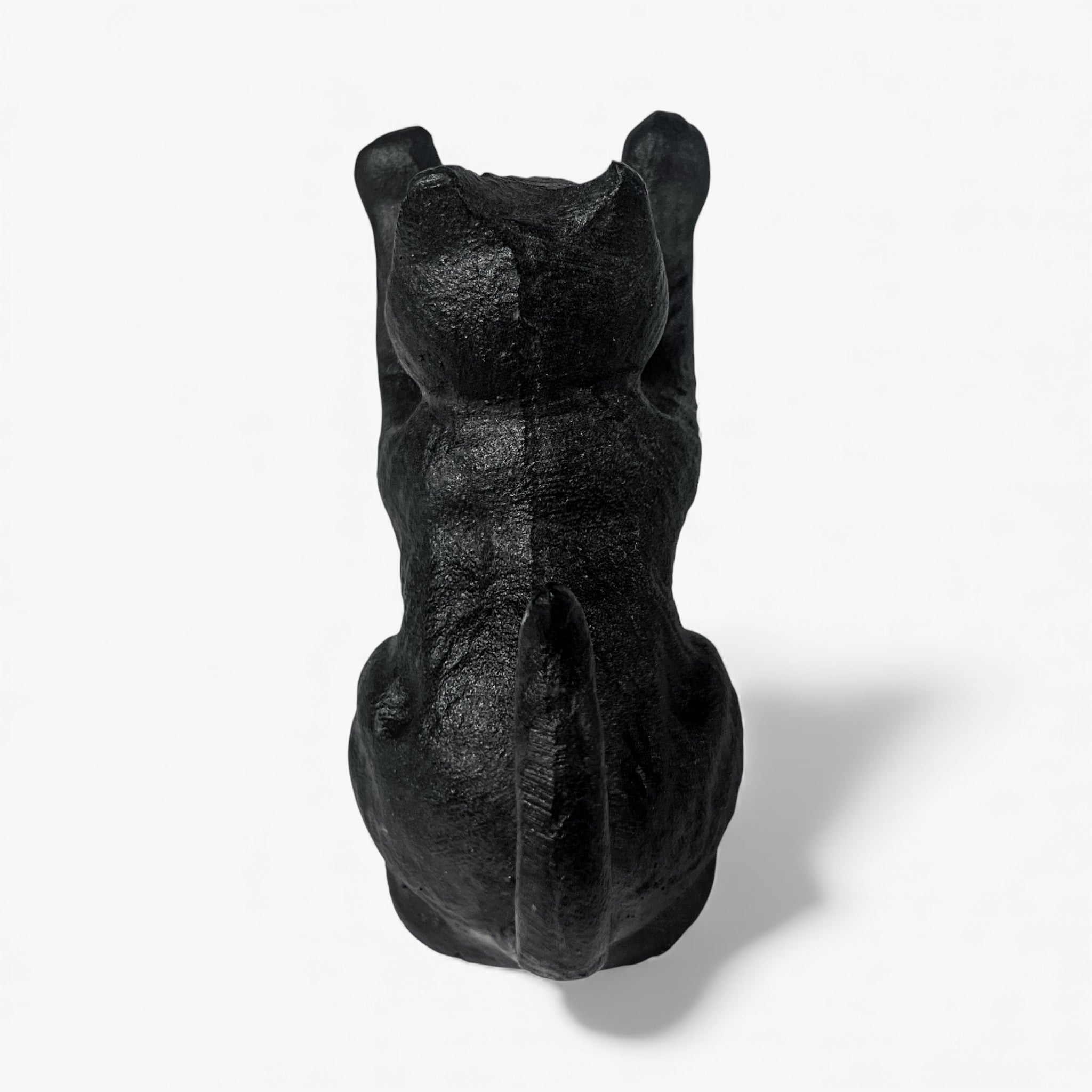 Front view of black cast iron cat door wedge sitting pose with ears visible textured surface detail