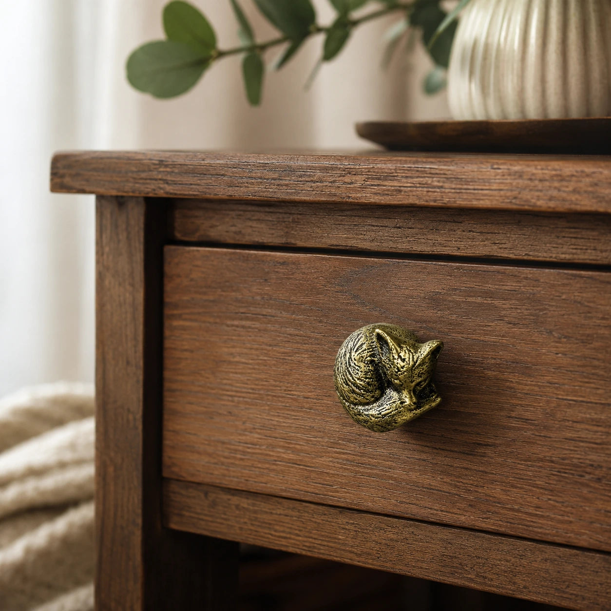 Angled view of brass fox drawer knob on a wooden nightstand