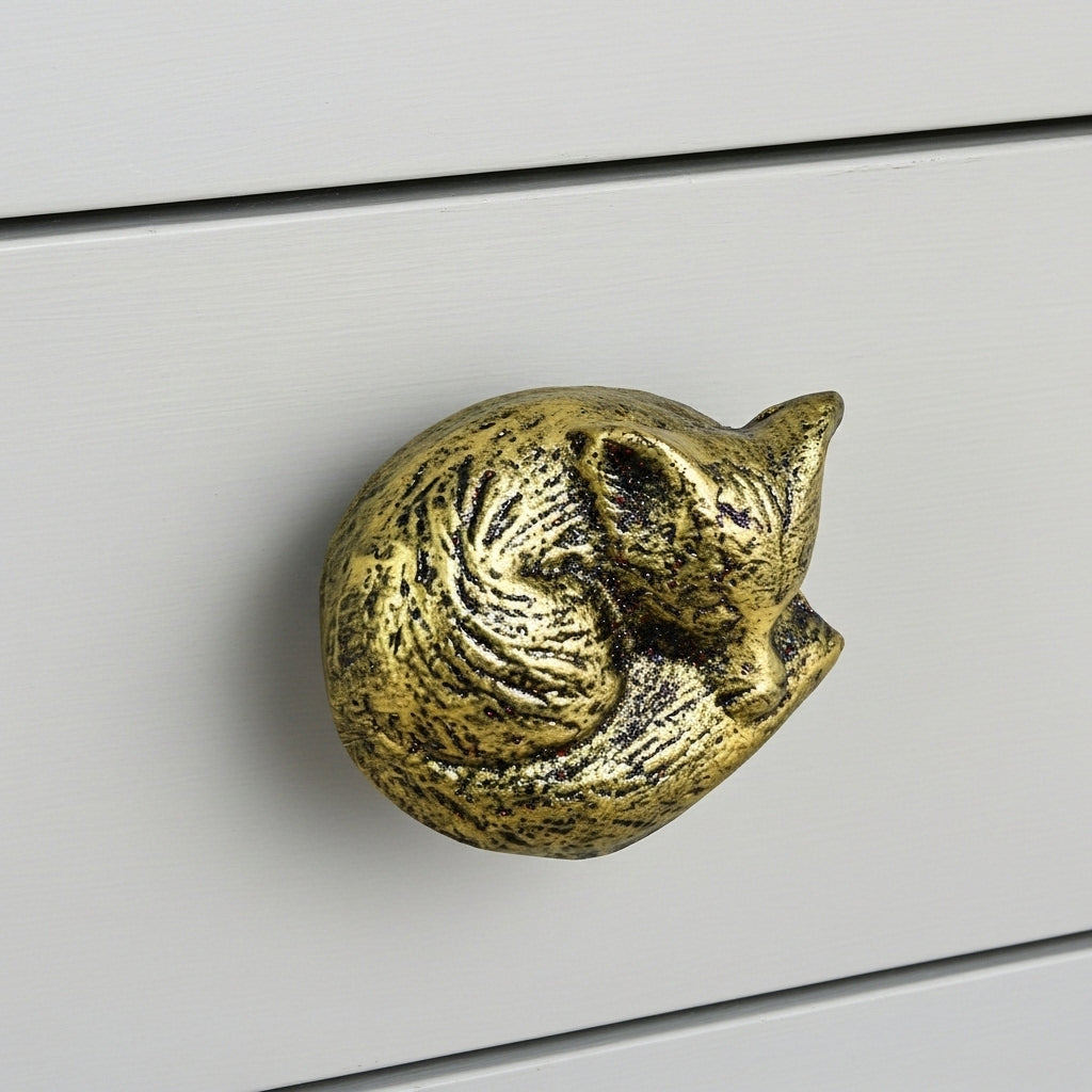 Gold cast iron fox drawer knob with detailed surface texture on white drawer