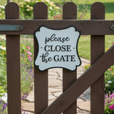 Cast iron close gate wall sign, white with black border and text, decorative outdoor plaque