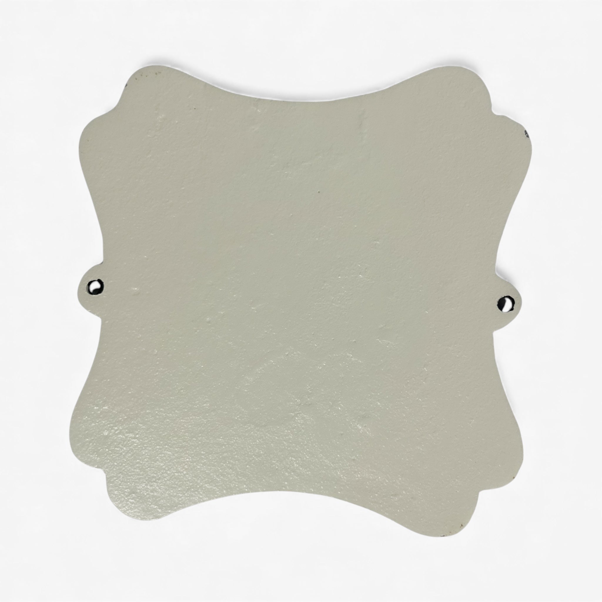 Cream colored cast iron decorative plaque with scalloped edges, mounting holes