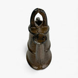 Bottom-up detail of cast iron watering can statue highlighting form and aged textured finish