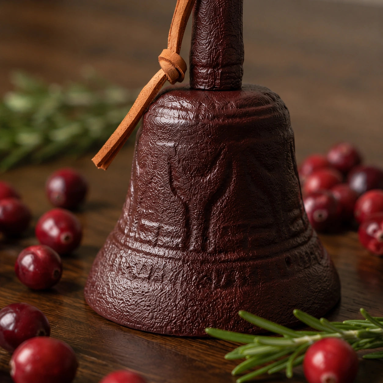 Close view of burgundy cast iron hand bell with textured finish and leather strap, SKU GB78097