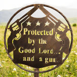 Rustic metal wall sign with gun and star design reading Protected by the Good Lord and a gun