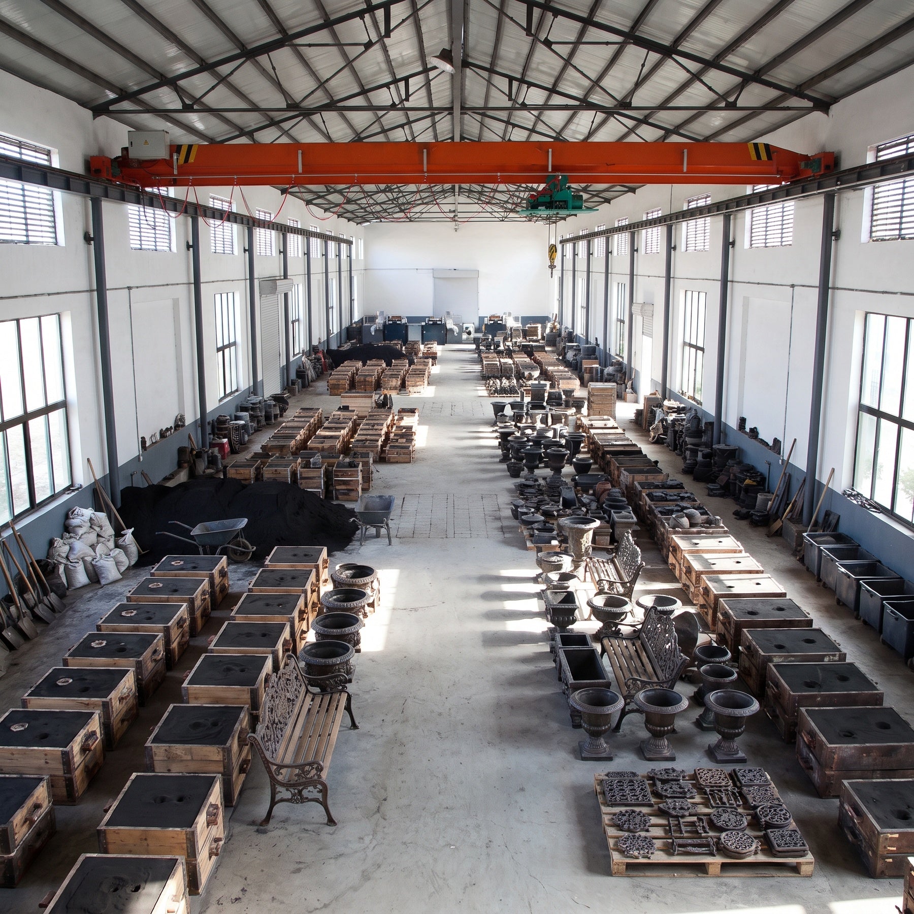 Cast iron garden décor, molds, and inventory inside a bright foundry production hall.